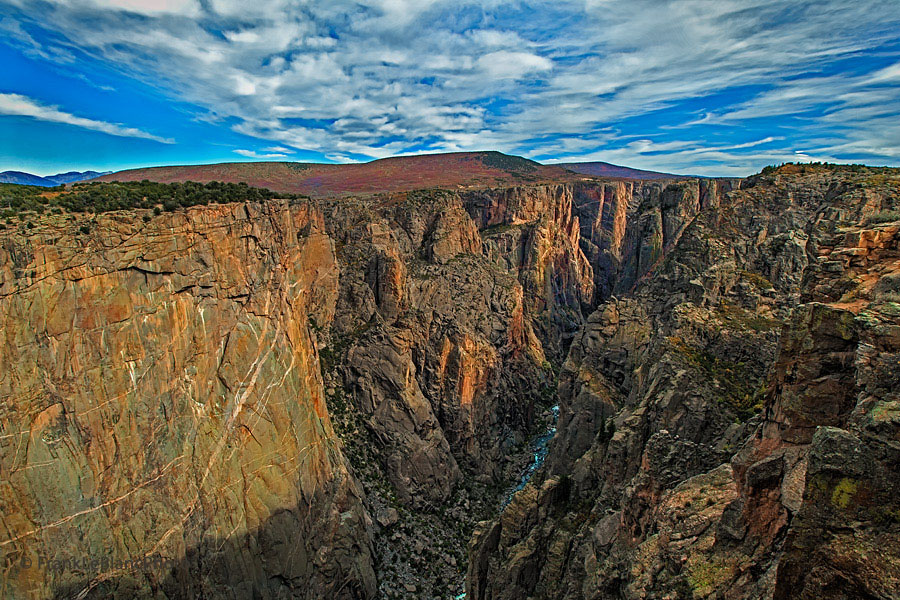 Looking into the Black Canyon's shadows a aqua blue strand of the Gunnison river appears 1800 feet below the rim. From this distance...