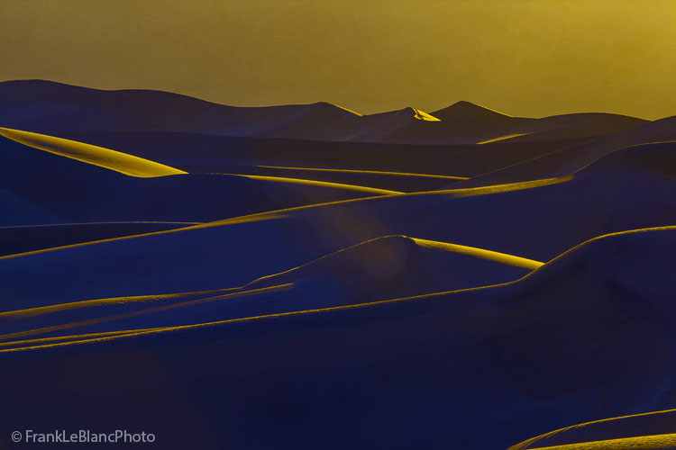 Mesquite Flat Dunes at sunset presents a scene of layer upon layer of intersecting lines and lighted shapes. Yellow light is...