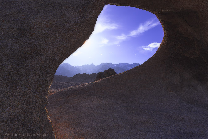 Looking through curvilinear lines of granite texture.  An open window reveals a brilliantly lighted eastern sierra nevada mountain...