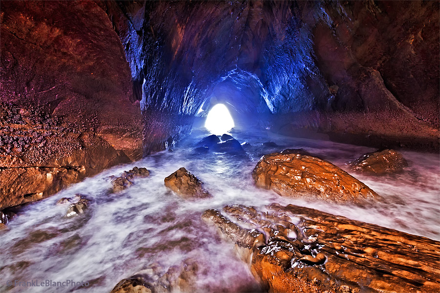 Outgoing tide inside of a large sea cave. Blinding light at the end of the tunnel and the booming sound of waves crashing outside...